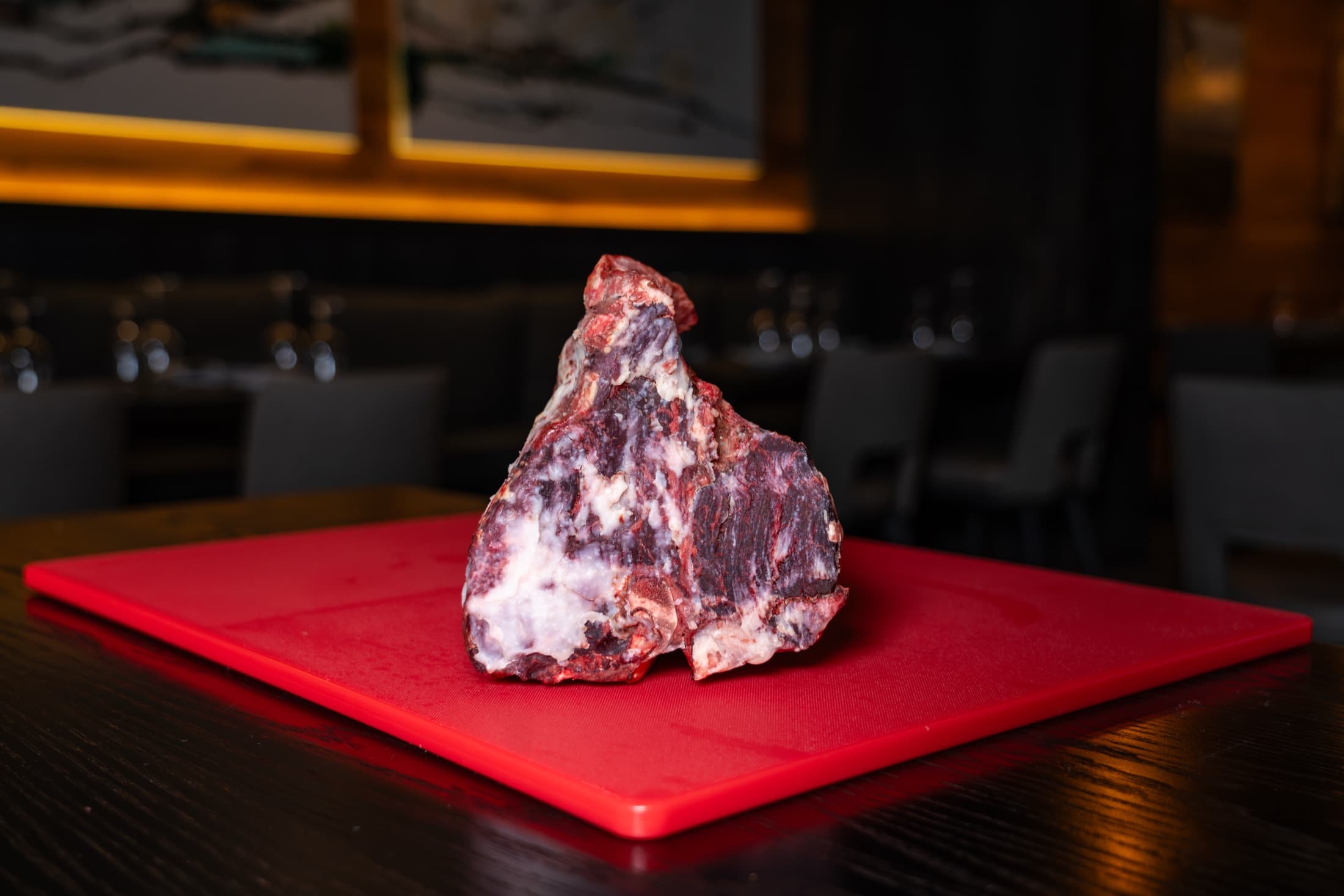 Dry-aged beef for porterhouse steaks, its dark aged crust still untrimmed, on a cutting board in the CHR Steak dining room