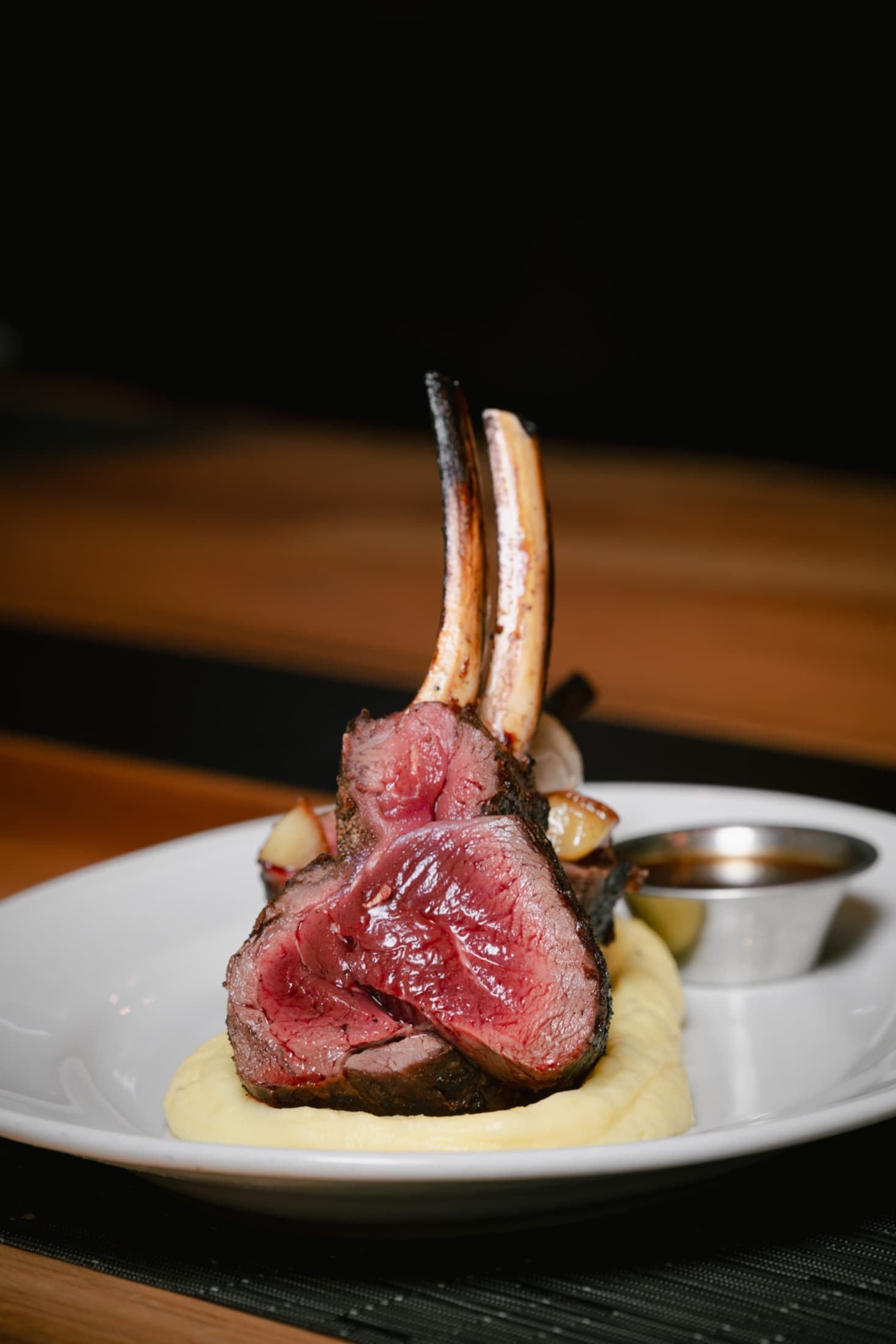 A carved game rack plated over puree with sauce on the side at CHR Steak in Gainesville, Georgia