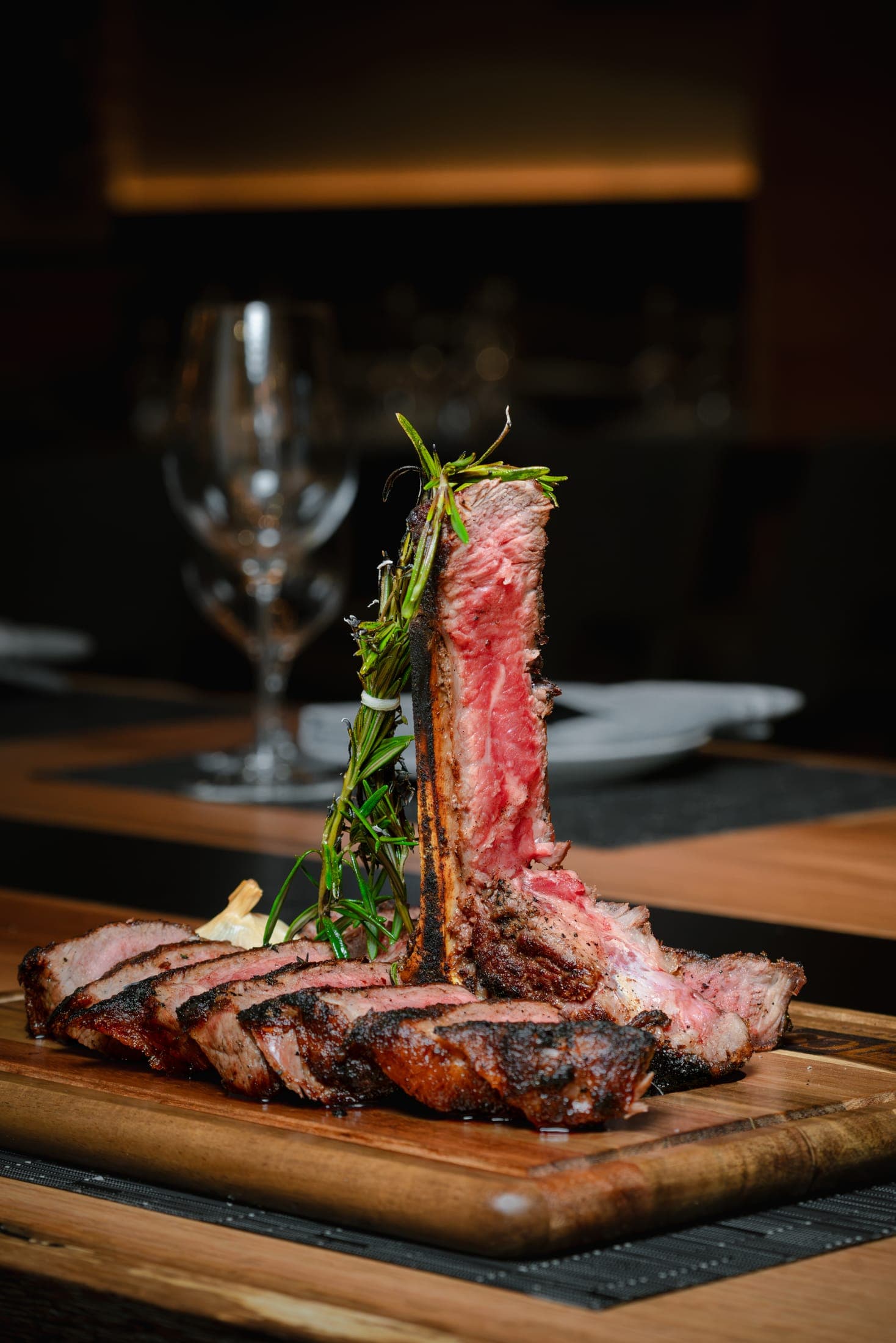 Dry-aged USDA Prime porterhouse steak sliced and presented upright on a wooden board