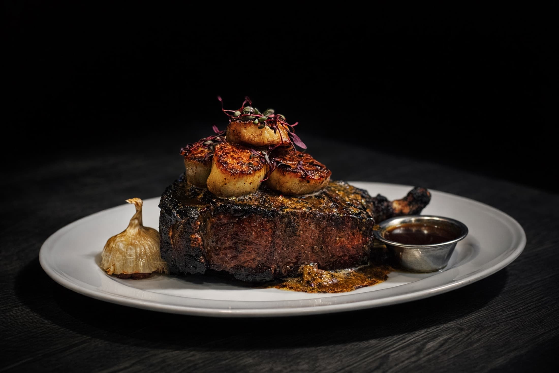 Plated ribeye steak with seared scallops at CHR Steak