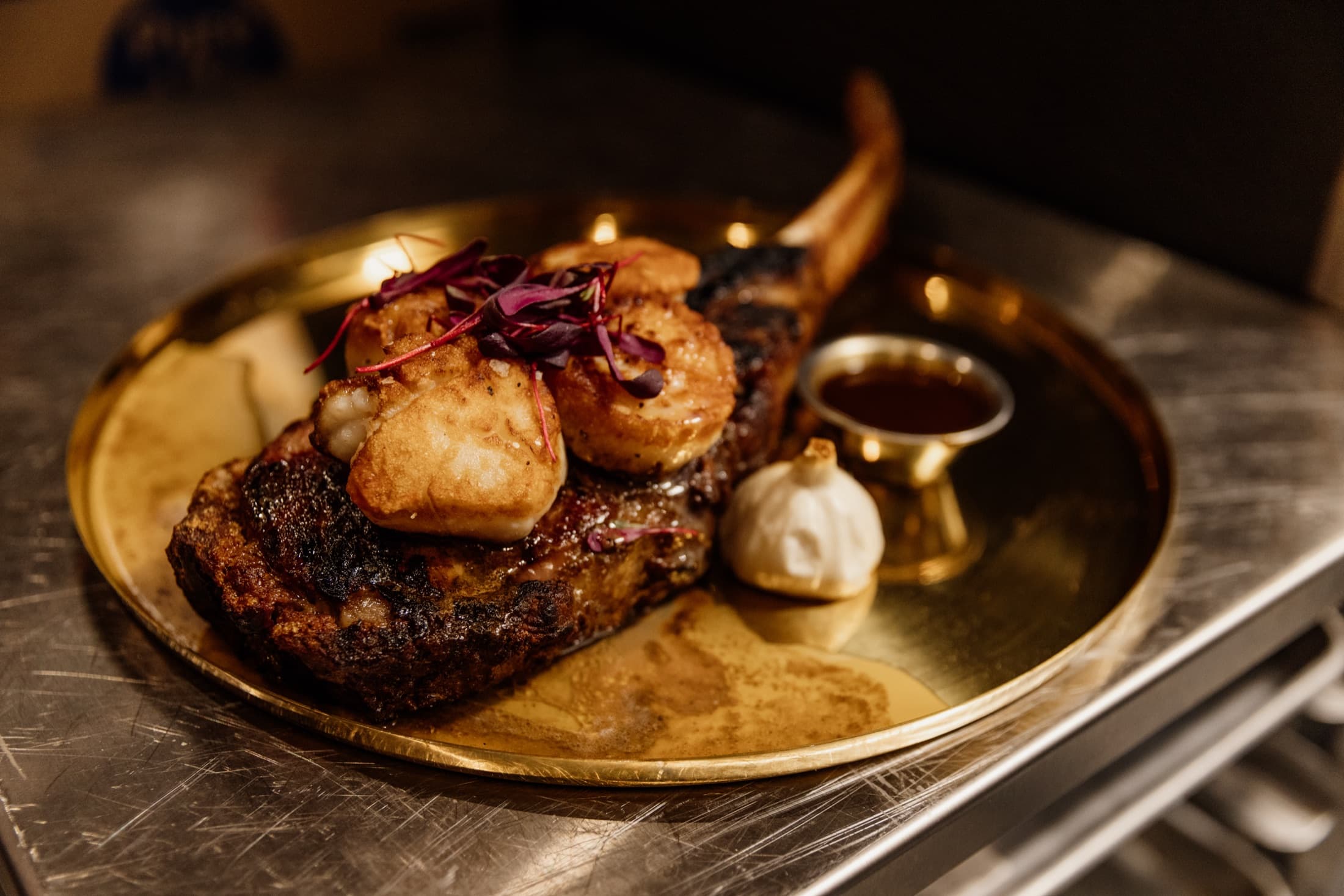 Dry-aged tomahawk steak finished with seared scallops at CHR Steak