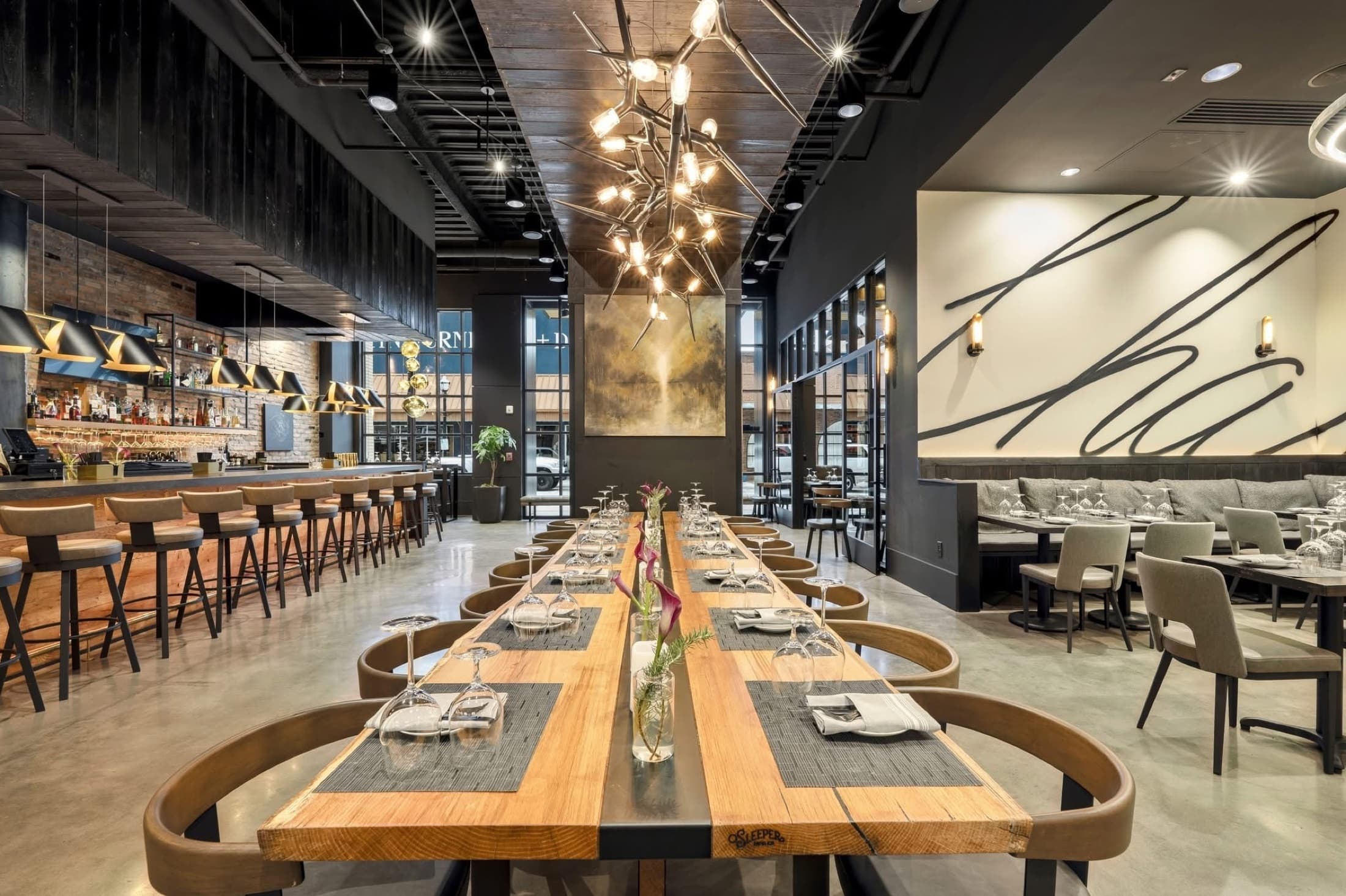 Communal dining table beneath the script wall at CHR Steak