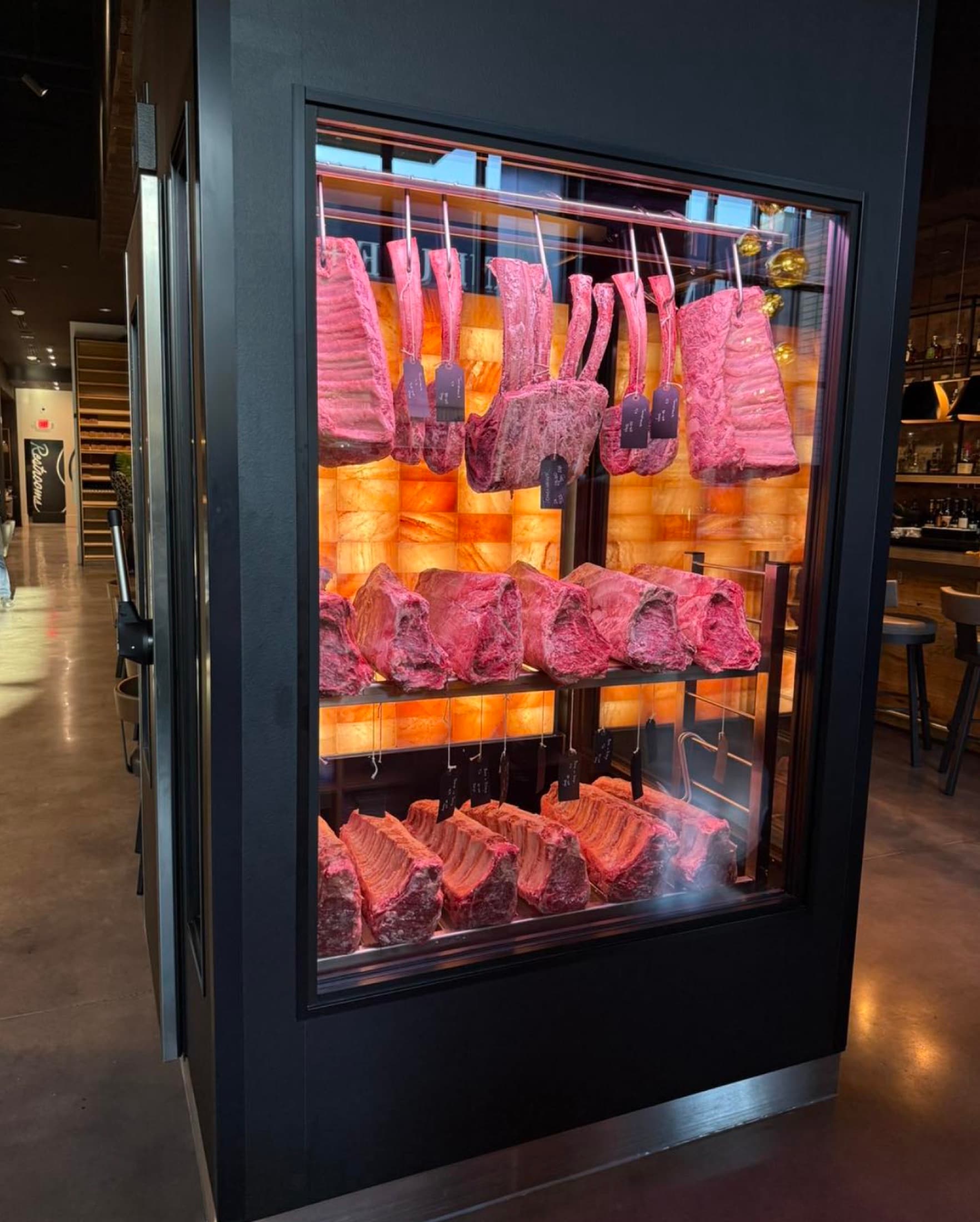 In-house dry-aging room with prime beef behind glass at CHR Steak