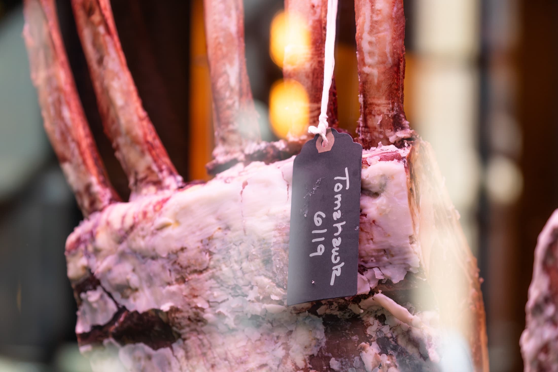 A tomahawk rib rack aging in the CHR Steak dry-age room, with a handwritten tag