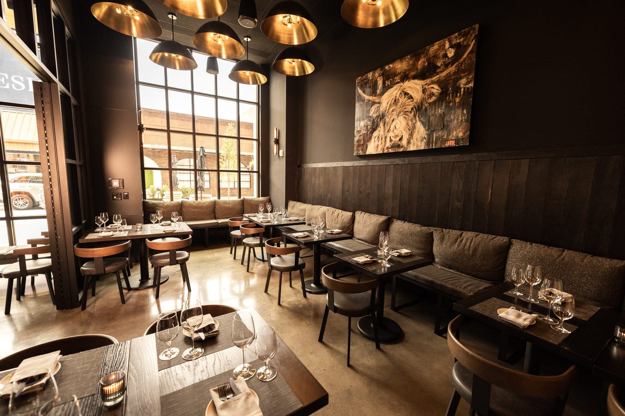 The private dining room at CHR Steak with banquette seating, brass pendant lights, and a wall of windows