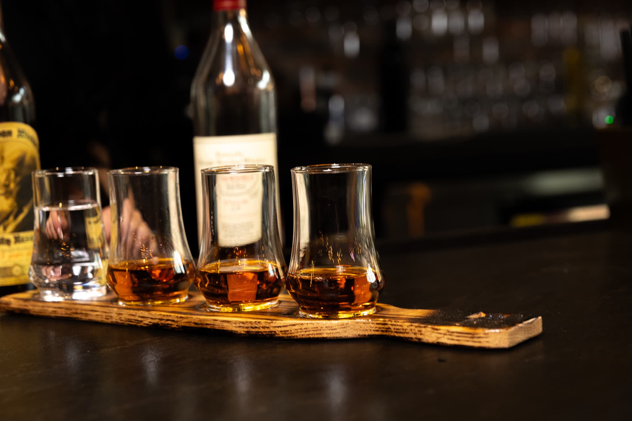 A four-pour bourbon tasting flight in tulip glasses on a barrel stave board at the bar at CHR Steak in Gainesville, Georgia