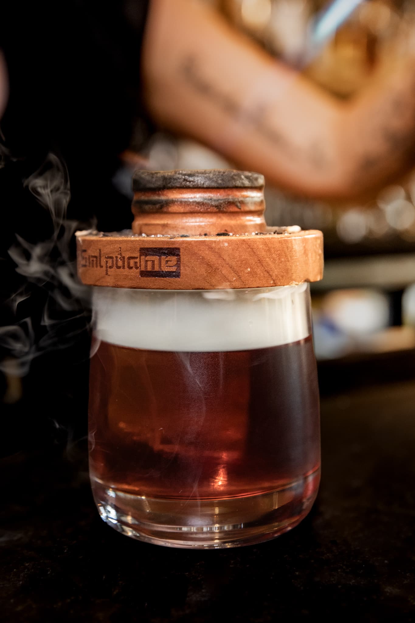 A whiskey cocktail finished under a smoking wooden press at the bar at CHR Steak in Gainesville, Georgia