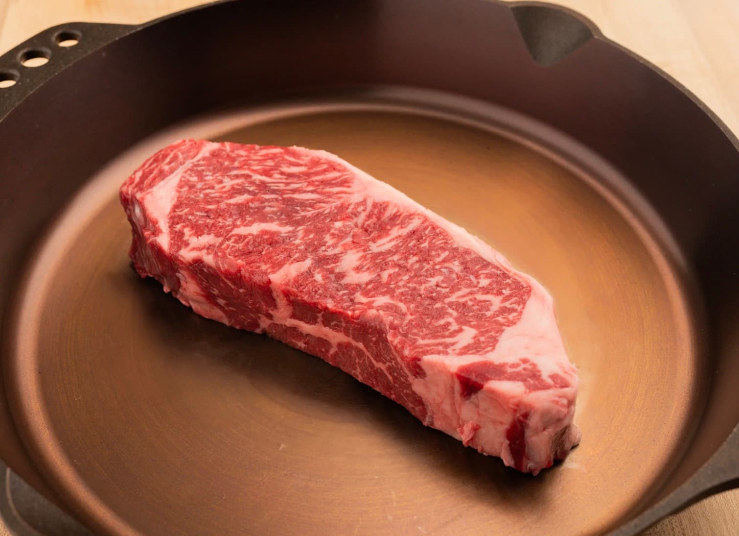 A raw American Wagyu strip steak with fine marbling running through the whole cut