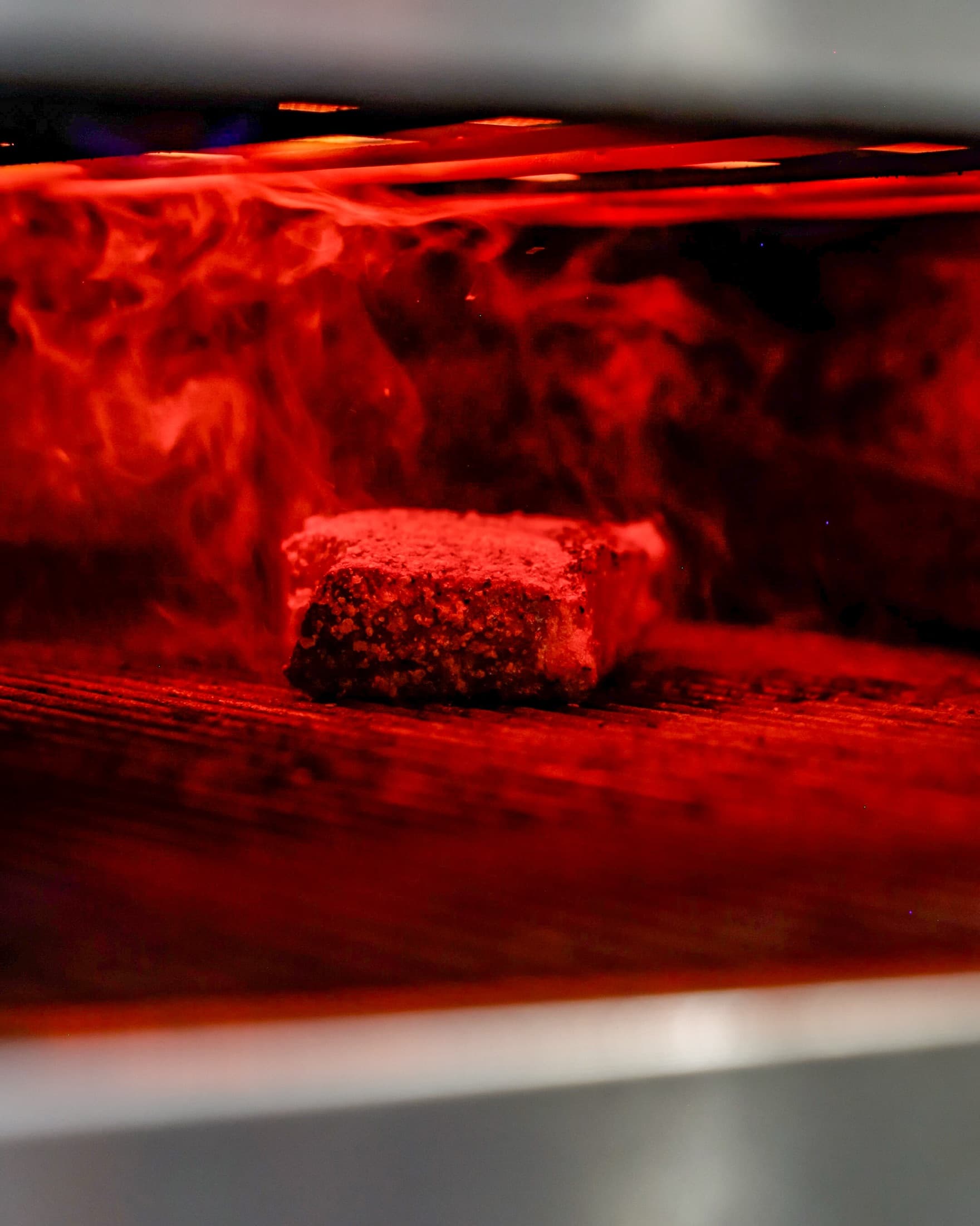 A steak searing inside the glowing infrared grill in the kitchen at CHR Steak in Gainesville, Georgia